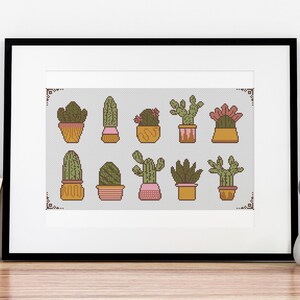 Peut inclure: Une impression encadrée d'une collection de dix cactus différents en pots. Les cactus sont tous dans différentes nuances de vert et de brun, et les pots sont un mélange d'orange et de rose.