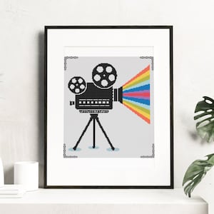 Puede incluir: Una ilustración en blanco y negro de un proyector de cine vintage con un arcoíris de colores que salen del objetivo.