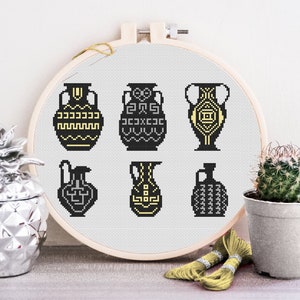 May include: A cross-stitch embroidery hoop featuring six black and yellow Greek-style amphorae designs.
