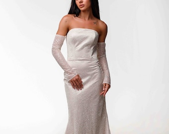 May include: A strapless, floor-length ivory gown with a subtle textured pattern. The dress features a fitted bodice and a flared skirt. Matching lace sleeves extend from the upper arms to the wrists. The gown is suitable for formal events.