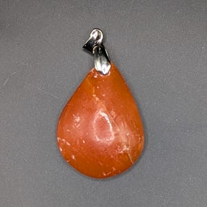 Peut inclure: Un pendentif en forme de larme en cornaline orange avec une bélière en argent.