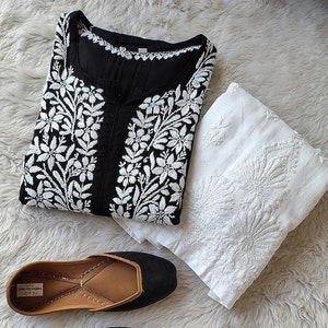 May include: A black and white embroidered kurta with a white dupatta and a pair of black leather shoes.