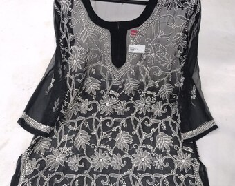 May include: Black sheer tunic with white embroidery featuring a floral pattern. The tunic has a V-neck and 3/4 sleeves.
