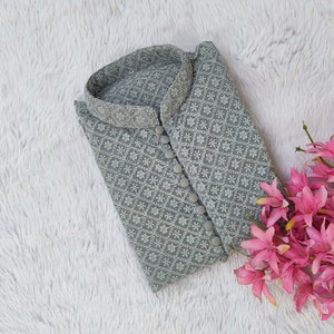 Pu&ograve; includere: Una kurta grigia ricamata con un motivo floreale bianco e chiusura con bottoni.