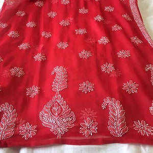May include: A red chiffon fabric with white embroidery in a floral and paisley pattern.
