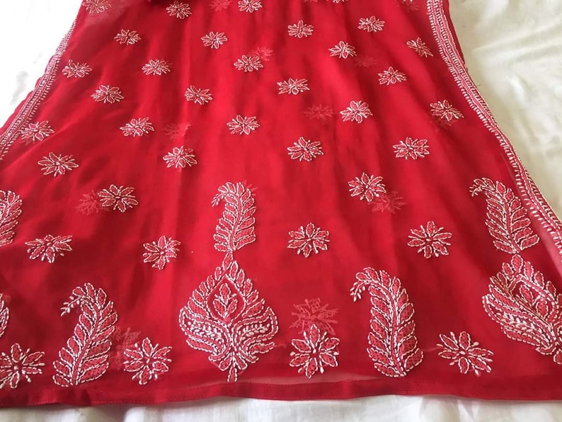 May include: A red chiffon fabric with white embroidery in a floral and paisley pattern.