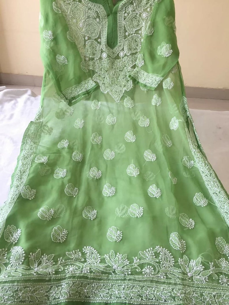 May include: A light green chiffon tunic with white embroidery. The embroidery features floral and paisley designs. The tunic has a round neckline and three-quarter sleeves.