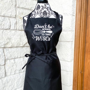 May include: Black apron with a white graphic that says "Don't be afraid to take risks" with a whisk graphic.
