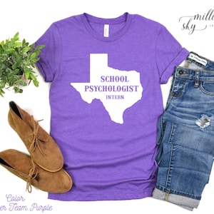 May include: Purple t-shirt with a white outline of the state of Texas. The text "School Psychologist Intern" is inside the outline.