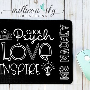 May include: Black mouse pad with white text that reads "School Psych Love Inspire" and "Ms Mackey". The text is stylized with a school building, pencils, a lightbulb, and a circle.