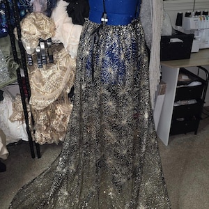 Peut inclure: Une jupe en tulle noir avec des &eacute;toiles dor&eacute;es scintillantes. La jupe est longue et fluide, et elle serait parfaite pour une occasion sp&eacute;ciale.