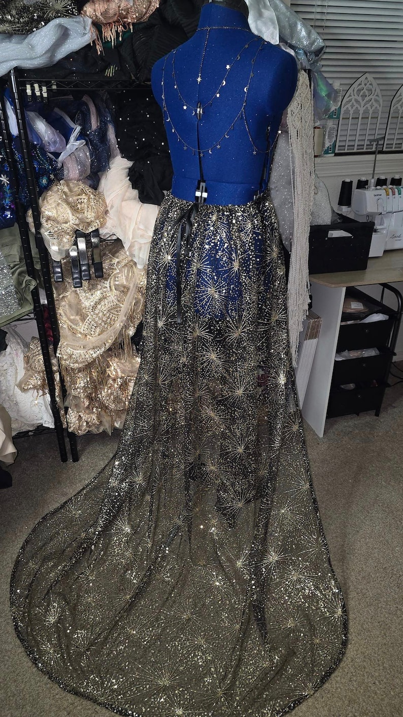 Peut inclure: Une jupe en tulle noir avec des &eacute;toiles dor&eacute;es scintillantes. La jupe est longue et fluide, et elle serait parfaite pour une occasion sp&eacute;ciale.
