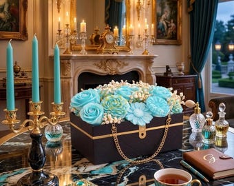 May include: A luxurious interior with a black and gold box overflowing with turquoise flowers. A gold chain handle adorns the box. A marble table displays a teacup, a small jewellery box, and a candelabra with turquoise candles.