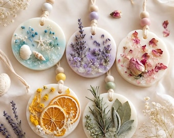 May include: Five circular wax air fresheners with dried flowers and botanicals. Each has a string for hanging and wooden beads. Scents include lavender, rose petals, dried orange slices, and seashells.