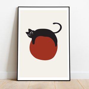 Puede incluir: Un gato negro con ojos grandes est&aacute; acostado sobre un c&iacute;rculo rojo. El gato est&aacute; mirando hacia el lado izquierdo de la imagen. El fondo es de color beige claro.
