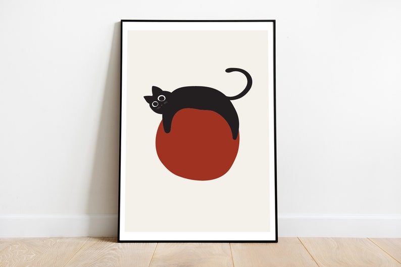 Puede incluir: Un gato negro con ojos grandes est&aacute; acostado sobre un c&iacute;rculo rojo. El gato est&aacute; mirando hacia el lado izquierdo de la imagen. El fondo es de color beige claro.