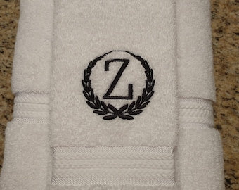 May include: Two white bath towels with a black embroidered wreath and the letter "Z" in the center.