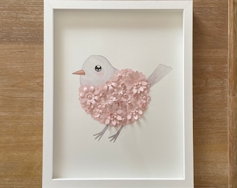 May include: A white bird with pink paper flowers covering its body. The bird is depicted in a white frame.