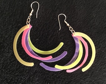 May include: A pair of earrings with three layered crescent shapes in yellow, pink, and purple.