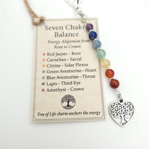 May include: A chakra balance charm with seven colorful gemstone beads and a silver-tone heart-shaped Tree of Life charm. The charm includes a tag with text describing the chakra energy alignment from root to crown.