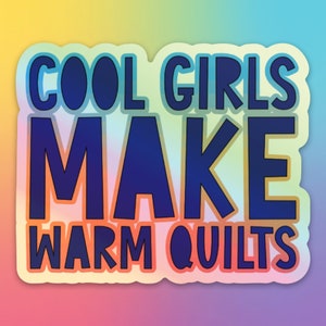 May include: A sticker with a rainbow gradient background and white border. The text "COOL GIRLS MAKE WARM QUILTS" is in blue with a black outline.