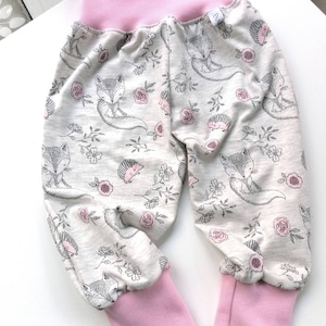 Könnte beinhalten: Graue und rosa Babyhose mit Fuchs- und Igel-Druck. Die Hose hat einen rosa elastischen Bund und rosa Bündchen.