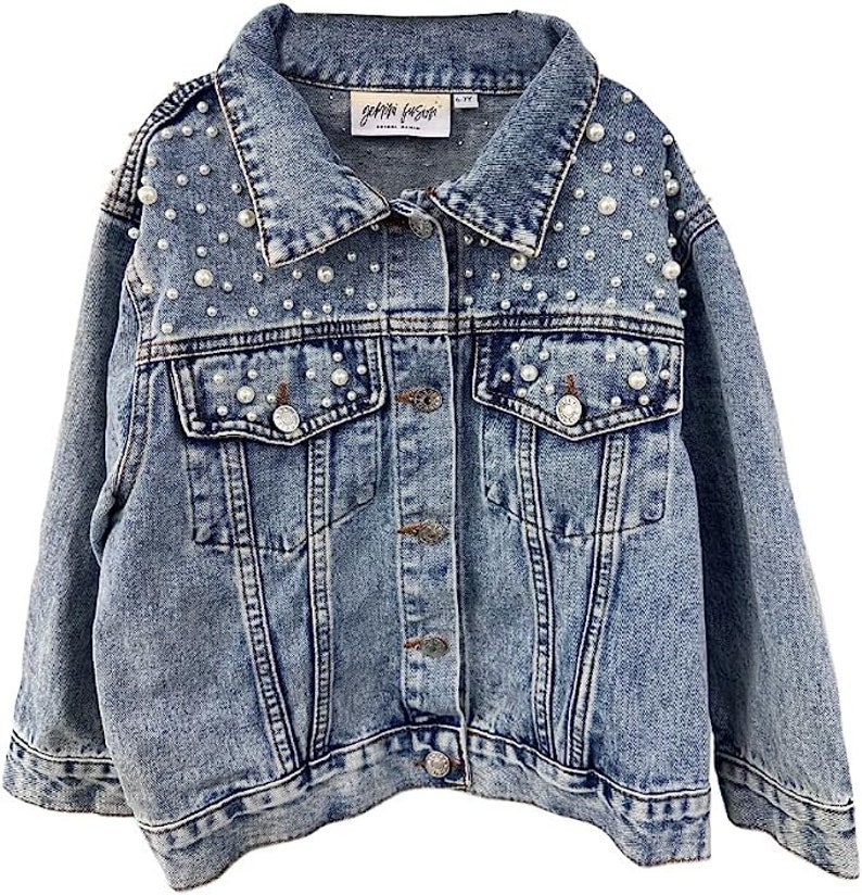 Może przedstawiać: Jasnoniebieska kurtka dżinsowa z perłami. Kurtka ma klasyczny kołnierz, zapięcie na guziki, dwie kieszenie na piersi i dwie kieszenie boczne. Etykieta zawiera nazwę marki "gemma fosati".