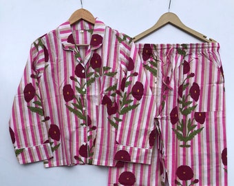 May include: Pink and white striped pajama set with a floral print. The top has a button-up front and a collar. The pants have an elastic waistband and a drawstring.