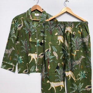 Puede incluir: Conjunto de pijama verde con estampado de jungla con cebras, leopardos, tucanes y palmeras.