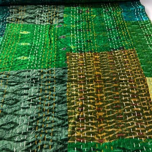 May include: Green and brown patchwork fabric with a quilted texture. The fabric is made of silk and has a subtle sheen.