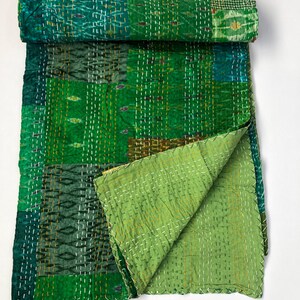 May include: A green kantha quilt with a patchwork design. The quilt is made of recycled saris and is hand-stitched. It is a traditional Indian textile.