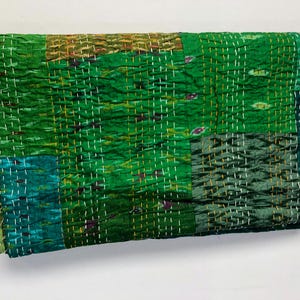 May include: A green kantha quilt with a patchwork design. The quilt is made of recycled saris and is hand-stitched. It has a soft, textured feel and is perfect for adding a touch of bohemian style to your home.