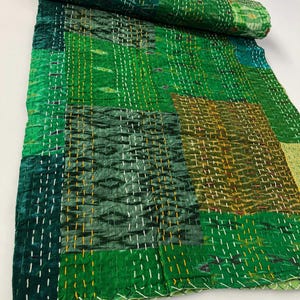 May include: A green kantha quilt with a patchwork design. The quilt is made of recycled saris and is hand-stitched with a running stitch. The quilt is perfect for adding a touch of bohemian style to your home.