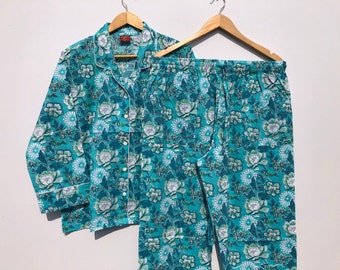 May include: A teal blue pajama set with a white floral print. The top has a collared neckline and long sleeves. The pants have an elastic waistband.