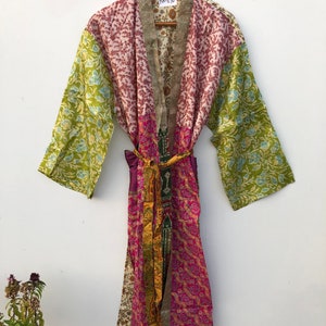 May include: A multi-colored silk robe with a patchwork design. The robe has a green, pink, and white floral pattern. The robe has a purple sash and a tag that says "NK-610".