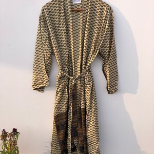 May include: A cream-colored robe with a black and brown floral print. The robe has a tie belt and a label that says "NK-683".