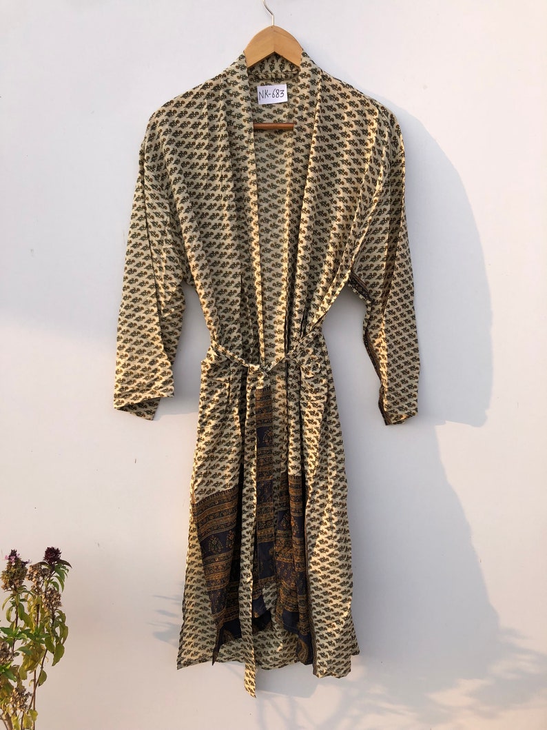 May include: A cream-colored robe with a black and brown floral print. The robe has a tie belt and a label that says "NK-683".