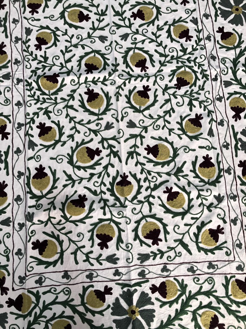 May include: White fabric with intricate embroidery of green vines and yellow and burgundy pomegranates.