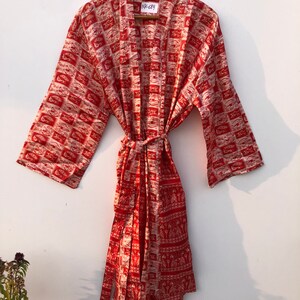 May include: Red and white patterned silk robe with a tie belt. The robe has a label that says "NK-Say".