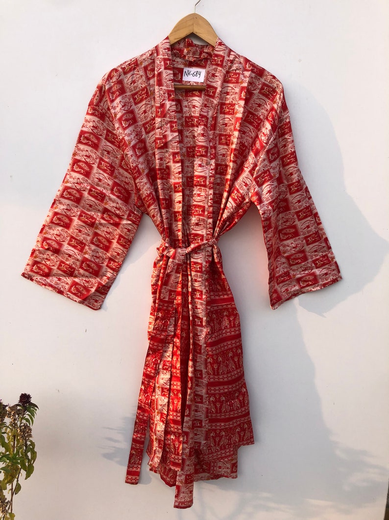 May include: Red and white patterned silk robe with a tie belt. The robe has a label that says "NK-Say".