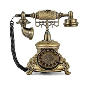 May include: An antique brass-coloured rotary dial telephone. The phone features a detailed floral design on the base and a classic handset. The coiled cord is black. The phone has a vintage aesthetic.