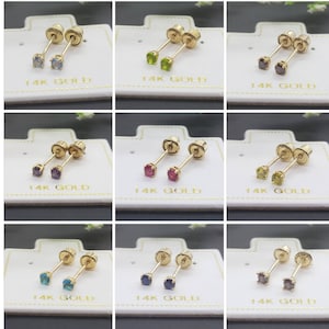 Peut inclure: Neuf paires de boucles d'oreilles en or 14 carats avec des pierres précieuses de différentes couleurs. Les boucles d'oreilles sont présentées sur des cartes blanches avec le texte "14K GOLD" imprimé sur chaque carte.