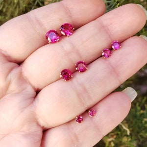 May include: Five pairs of small, round, pink gemstone earrings. The earrings are set in gold.