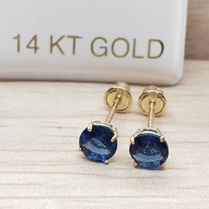 Op de afbeelding: Een paar 14 karaats gouden oorbel studs met blauwe edelstenen.