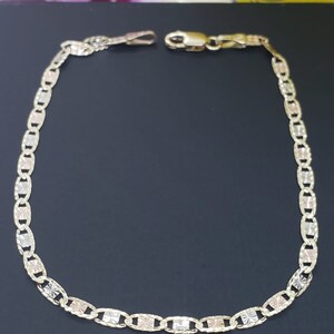 Puede incluir: Un brazalete de cadena de oro con un delicado dise&ntilde;o de eslabones ovalados. La cadena est&aacute; hecha de tres colores de oro diferentes: amarillo, blanco y rosa.
