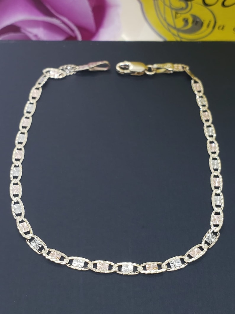 Puede incluir: Un brazalete de cadena de oro con un delicado dise&ntilde;o de eslabones ovalados. La cadena est&aacute; hecha de tres colores de oro diferentes: amarillo, blanco y rosa.