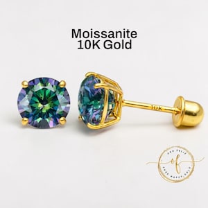 Może przedstawiać: Para kolczyków z moissanitem w złotej oprawie. Kamienie moissanitowe mają żywy, opalizujący kolor. Kolczyki są oznaczone jako "Moissanite 10K Gold". Kolczyki znajdują się na białym tle.