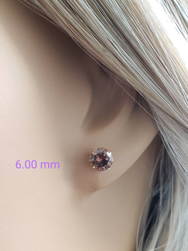 Peut inclure: Une paire de boucles d'oreilles en or avec une pierre ronde de couleur violette fonc&eacute;e de 6,00 mm de diam&egrave;tre.