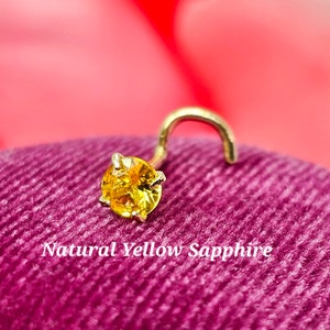 May include: A gold nose ring with a small, round, yellow sapphire gemstone.  Natural Yellow Sapphire.