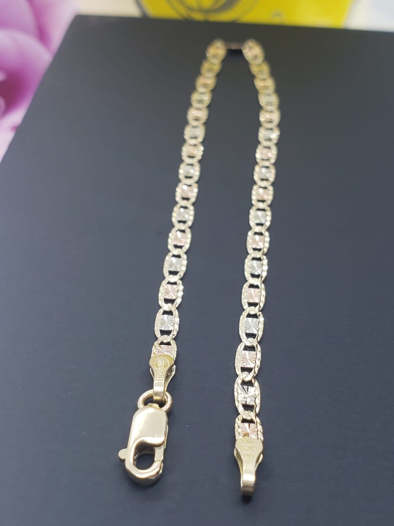 Puede incluir: Un brazalete de cadena de oro con un dise&ntilde;o tricolor. La cadena est&aacute; hecha de tres colores diferentes de oro: amarillo, blanco y rosa. El brazalete tiene un cierre de langosta.